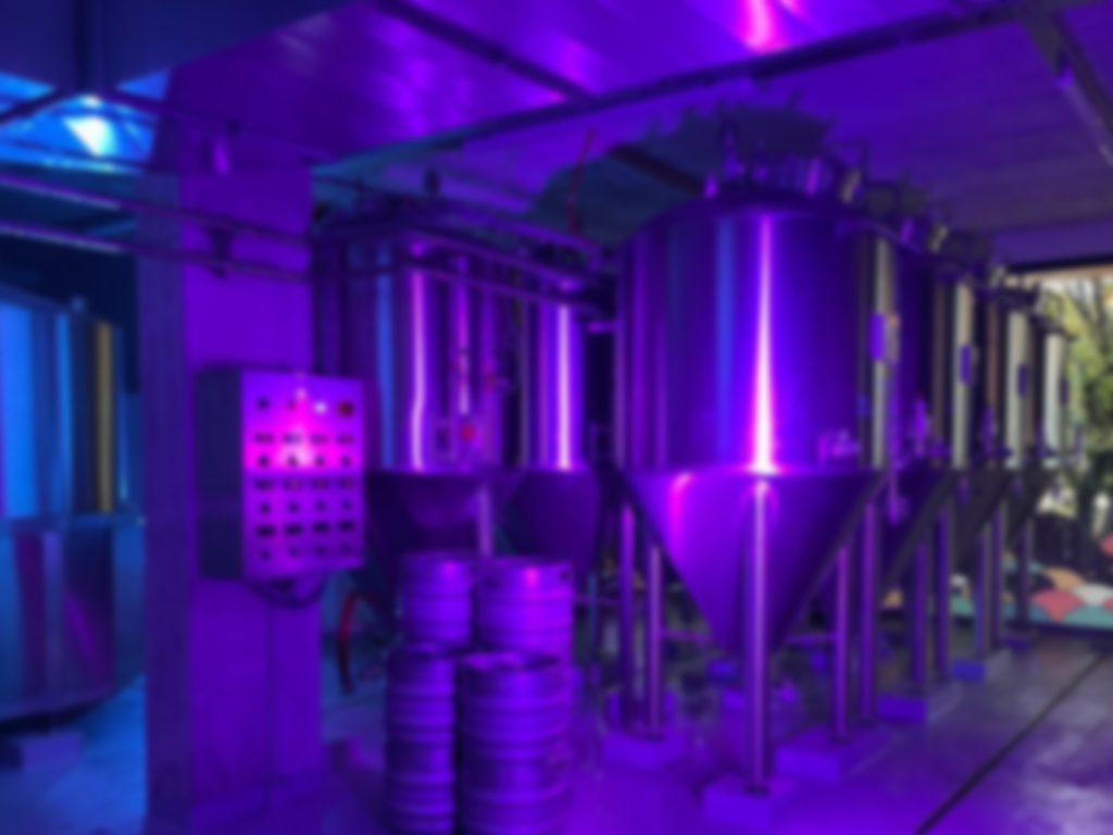 Cuves de fermentation en inox de la microbrasserie Bloom Pop à Rennes éclairées par des néons violets.